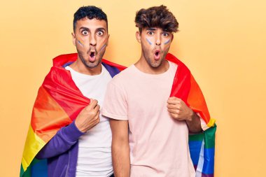 Gökkuşağı lgbtq bayrağı giyen genç eşcinsel çift ağzı açık kalmış, korkmuş ve şaşkına dönmüştü. 