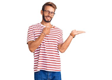 Sakallı, sıradan giyinen, gözlüklü yakışıklı sarışın adam kameraya hayret ediyor ve gülümsüyor.. 