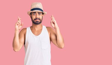 Yaz şapkası takan genç İspanyol adam umut ve gözlerin kapalı gülümseyerek el sallıyor. Şans ve batıl inançlar. 