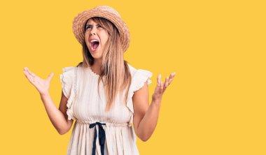 Yazlık şapka ve tişört giyen genç ve güzel bir kadın. Deli gibi bağırıyor, agresif bir ifadeyle bağırıyor ve kollarını kaldırıyor. hüsran kavramı. 