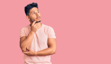 Yakışıklı Latin Amerikalı gündelik kıyafetler giyen ciddi yüzlü eli çeneli soruyu düşünen kafa karıştırıcı bir fikir. 