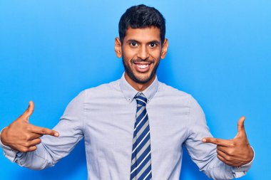 İş kıyafetleri giyen, kendine güvenen, gülümseyen, kendini gururlu ve mutlu gösteren genç Latin bir adam.. 