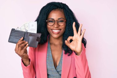 Güzel Afrikalı bir kadın cüzdanı elinde tutuyor. Parmakla imza atıyor. Gülümsüyor. 