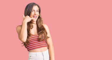 Güzel, beyaz bir kadın, günlük kıyafetler giyip gülümsüyor, telefonla el ve parmak hareketleri yapıyor, telefonda konuşuyor gibi. iletişim kavramları. 