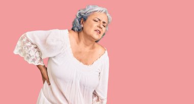 Beyaz saçlı, bohem tarzı sırtı ağrıyan, elleriyle dokunan, kaslı yaşlı bir kadın. 