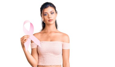 Genç ve güzel bir kadın elinde kanser farkındalığı pembe kurdele düşünme tavrı ve ayık bir ifade ile kendinden emin görünüyor. 