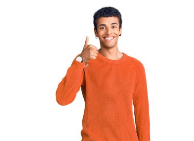 Genç Afrikalı Amerikalı günlük kıyafetler giyen mutlu ve pozitif gülümseyen, başparmağı mükemmel ve onay işareti yapan biri. 