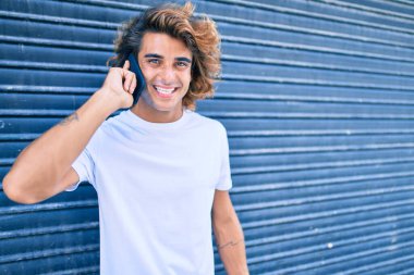 Genç İspanyol adam şehrin caddesinde akıllı telefondan konuşuyor.