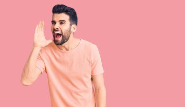 Sakallı, sıradan tişörtlü genç ve yakışıklı bir adam el pençe divan durup bağırıyor. iletişim konsepti. 