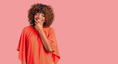 Genç Afro-Amerikan kadın günlük kıyafetler giyiyor kameraya bakıyor kollarını kavuşturup gülümsüyor ve çenesini kaldırıyor. Olumlu düşünmek. 