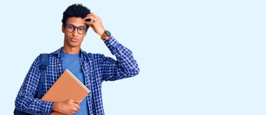 Afrika kökenli Amerikalı genç bir adam sırt çantası takıyor. Elinde kitap var. Alnındaki sorun yüzünden endişeli ve stresli. 