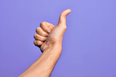 İzole edilmiş mor arka planda parmaklarını gösteren beyaz bir gencin eli başarılı bir onay jesti yapıyor. Başparmaklar yukarı, onaylama ve pozitif sembol ile.