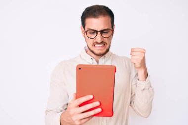 Dokunmatik ped kullanan genç yakışıklı adam öfkeyle bağırıyor, öfkeyle bağırıyor ve el kaldırıyor. 