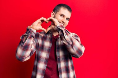 Gündelik tişört giyen genç yakışıklı aşık gülümseyen, elleriyle kalp sembolü yapan. romantik kavram. 