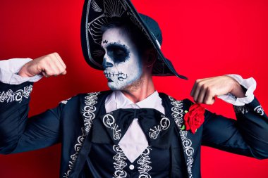 Ölü kostümü giyip Meksika 'ya giden genç adam kırmızı kollarına gururla gülümseyen kaslarını gösteriyor. fitness konsepti. 