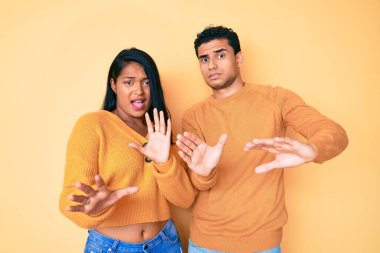 Güzel, Latin, genç bir çift, günlük kıyafetlerini giyerek korku ifadesinden korkar ve dehşete düşerler. El hareketlerini bırak, şok içinde bağır. panik konsepti. 