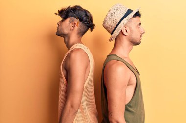 Yazlık giysiler giyen genç eşcinsel çift, rahat profil pozu veriyor, doğal bir yüz ifadesi ve kendine güvenen bir gülümseme.. 