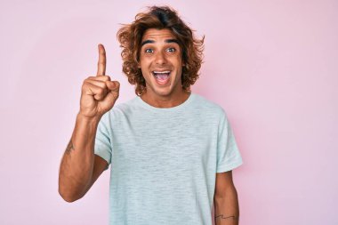Gündelik kıyafetler giyen genç İspanyol adam başarılı bir fikirle işaret ediyor. Heyecanlı ve mutlu. Bir numara.. 