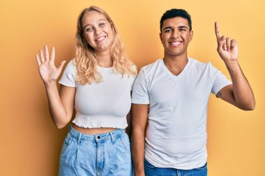 Irklar arası genç çift, beyaz tişört giyip altı numaralı parmaklarını gösterirken mutlu ve kendinden emin bir şekilde gülümsüyor.. 