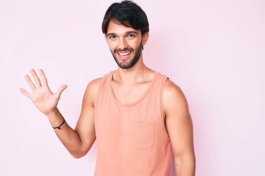 Yakışıklı, günlük kıyafetler giyen, beş numarayı gösterip işaret eden, kendinden emin ve mutlu gülümseyen İspanyol.. 