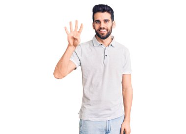 Sakallı, sıradan polo giyen, dört numarayı gösteren, kendinden emin ve mutlu bir şekilde gülümseyen genç yakışıklı bir adam.. 
