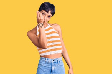 Kısa saçlı genç esmer kadın gündelik kıyafetler giyiyor. İtalyan jestleri yapıyor. Elleri ve parmakları kendine güvenen ifadeleri var. 