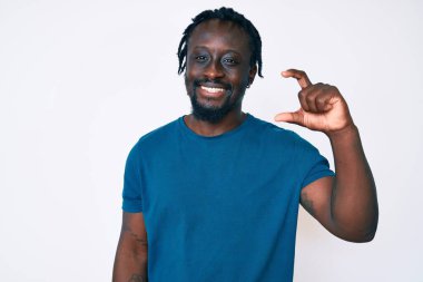 Saçları günlük kıyafetlerle örülmüş, el hareketleriyle küçük boy işaretler yaparak gülümseyen ve kendine güvenen genç Afro-Amerikan bir adam ve kamera. ölçüm kavramı. 