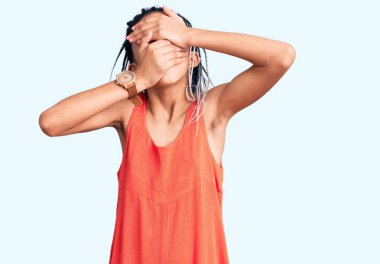 Hoş Afro-Amerikan kızı günlük kıyafetler giyip gözlerini ve ağzını ellerinle kapatmış, şaşırmış ve şok olmuş. duygu gizleme 