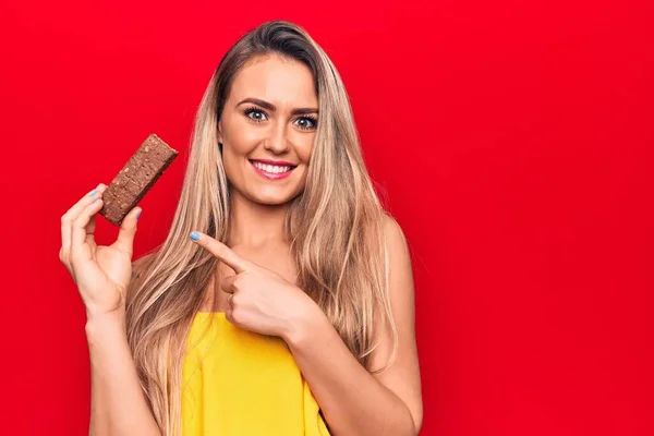 Joven Hermosa Mujer Rubia Comiendo Barra Proteína Chocolate Sobre Fondo — Foto de Stock