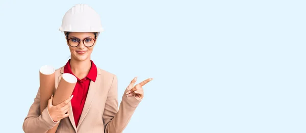 Jovem Mulher Bonita Vestindo Arquiteto Hardhat Óculos Segurando Plantas Sorrindo — Fotografia de Stock