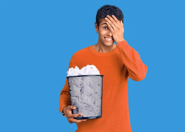 紙の箱を持っている若いアフリカ系アメリカ人の男頭の上に手で強調し 驚きと怒りの顔 — ストック写真