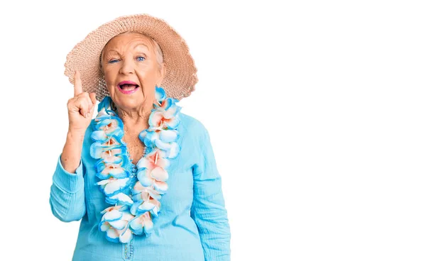 夏の帽子をかぶって青い目と灰色の髪をしたシニアの美しい女性とハワイのレイは 成功したアイデアで指を指しています 興奮して幸せよ 第1位 — ストック写真