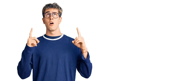Mladý Pohledný Muž Neformálním Oblečení Brýlích Užaslý Překvapený Vzhlíží Ukazuje — Stock fotografie