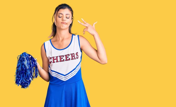 Young beautiful woman wearing cheerleader uniform shooting and killing oneself pointing hand and fingers to head like gun, suicide gesture.