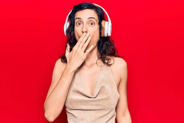 Young Beautiful Hispanic Woman Listening Music Using Headphones Covering Mouth — Stock Photo, Image