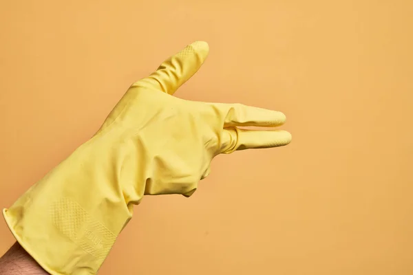 Ręka Białego Młodzieńca Rękawicą Czyszczącą Odizolowanym Żółtym Tle Gestykulująca Bronią — Zdjęcie stockowe
