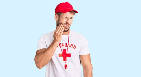 歯の痛みや歯の病気のために痛みを伴う表現で手で口に触れる笛を保持ライフガードのTシャツを着て若い白人男性 歯科医 — ストック写真