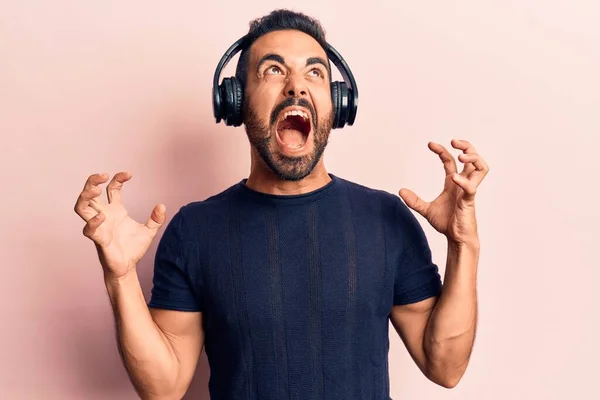 Young Hispanic Man Listening Music Using Headphones Crazy Mad Shouting — Stock Photo, Image