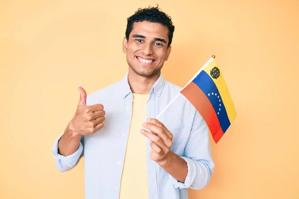 若いですハンサムなヒスパニック系の男を保持Venezuelanフラグ笑顔幸せと正 親指アップ行う優れた承認サイン — ストック写真