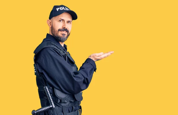 Young handsome man wearing police uniform pointing aside with hands open palms showing copy space, presenting advertisement smiling excited happy