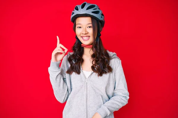 若い美しい中国の女の子は 成功したアイデアで指を指して自転車のヘルメットを着て 興奮して幸せよ 第1位 — ストック写真