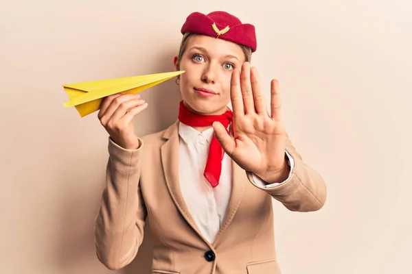 Νεαρή Όμορφη Ξανθιά Κοπέλα Φορώντας Στολή Αεροσυνοδού Κρατώντας Χάρτινο Αεροπλάνο — Φωτογραφία Αρχείου