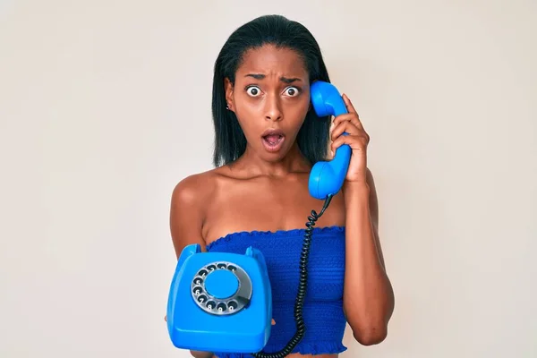 Joven Mujer Afroamericana Sosteniendo Teléfono Vintage Cara Choque Mirando Escéptico —  Fotos de Stock