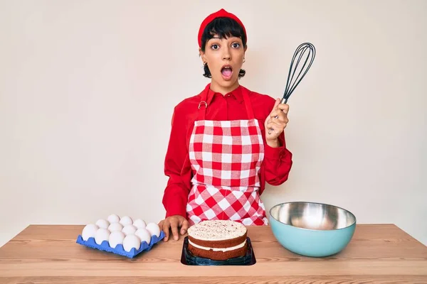 Piękna Brunetka Kobieta Gotowanie Ciasto Pomocą Piekarz Trzepaczka Przestraszony Zdumiony — Zdjęcie stockowe