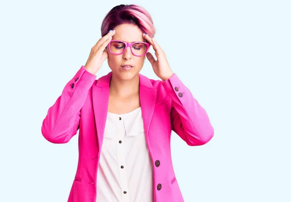 年轻美丽的女人 一头粉色的头发 身穿商务外套 戴着眼镜 由于疼痛和偏头痛 绝望和压力重重 手放在头上 — 图库照片