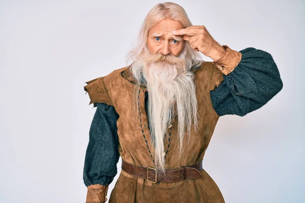 Gri saçlı, uzun sakallı, Viking kostümü giyen yaşlı bir adam alnındaki sivilceden memnun olmayan siyah noktalı çirkin bir enfeksiyon gösteriyor. sivilce ve deri problemi 