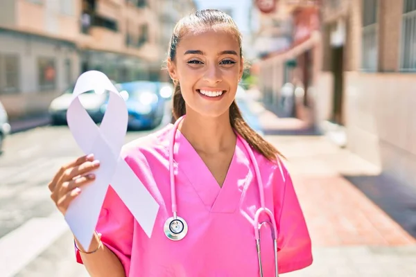 Young doctor woman holding white cancer ribbon walking at street of city.