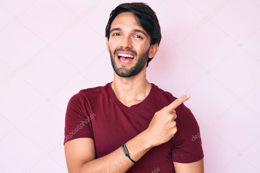 Handsome hispanic man wearing casual clothes smiling cheerful pointing with hand and finger up to the side 