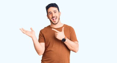 Gündelik kıyafetler giyen genç İspanyol adam kameraya hayret ediyor ve gülümsüyor.. 