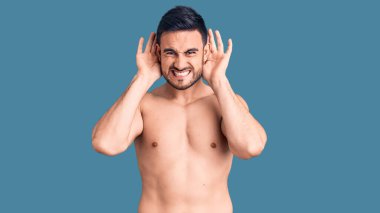 Mayo giyen genç yakışıklı adam iki elini de kulak hareketine sokmaya çalışıyor. Dedikoduya meraklı. İşitme sorunu, sağır 